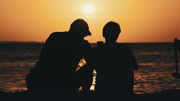 Silhouette Couple of MiddleAged Man and Woman at Sunset on the Beach By Ocean alt