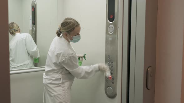 Woman Using Wet Wipe and Alcohol Sanitizer Spray To Clean an Elevator Push Button Control Panel