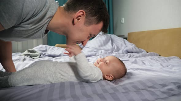 Young Father Plays with Newborn Baby Boy Making Son Laugh alt