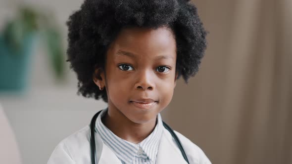 Cute Serious African American Kid Girl in Medical Clothes Dressed in White Coat Standing Indoors alt
