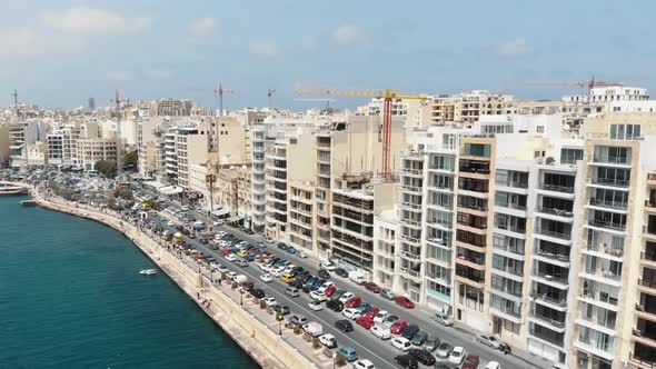 Aerial 4k footage flying towards a heavy trafficked area of a coastal city block of Sliema, Malta alt