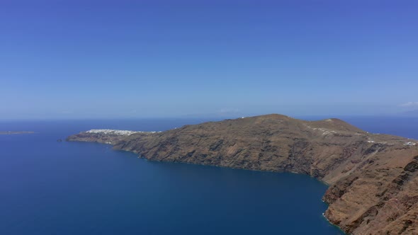 Slow panning panoramic drone shot of Oia in Santorini, Greece on a sunny day alt