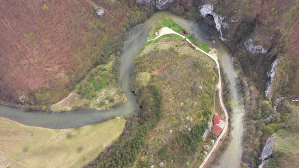 Aerial Above View of a Wild Mountain River Meander and a Gigantic Cave Entrance alt