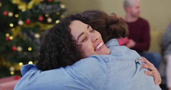Happy diverse male and female friends hugging at christmas time alt