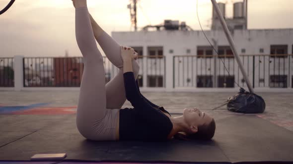 Woman in sportswear stretching and warm up before doing yoga on the rooftop in the evening. alt