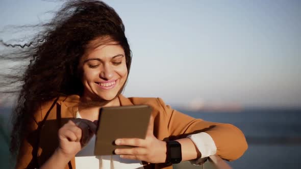 Smiling Young Fashionable Woman with Smartwatch Using Tablet Outdoors