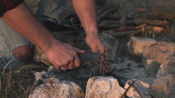 Man Hands Lighting a Fire Starting Campfire with Fire Starting Tools and Knife Making a Camp to Stay