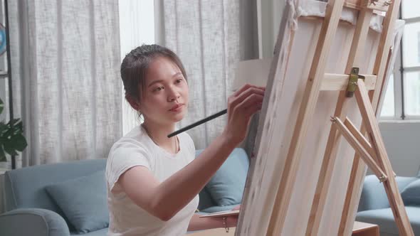 Asian Artist Girl Coming To Sit And Holding Paintbrush Mixed Colour Before Painting On The Canvas alt