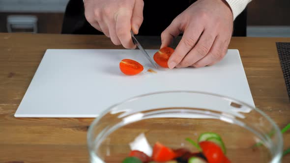 Chef cook man standing near table sliced fresh cherry tomato in home kitchen