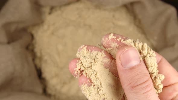 Human hand holds and presses a pinch of a ginger powder over a sac