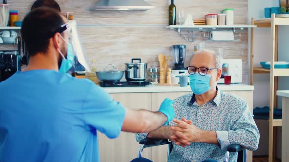 Social Worker Offering Pills to Disabled Senior Man alt