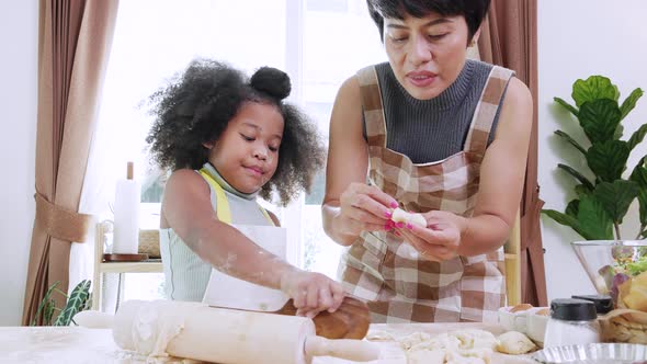 African American mom with little adorable kid preparing cookies dough in kitchen at home.