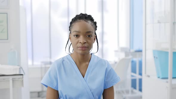 Crop View of Serious Afro  American Female Doctor Raising Head and Looking to Camera alt