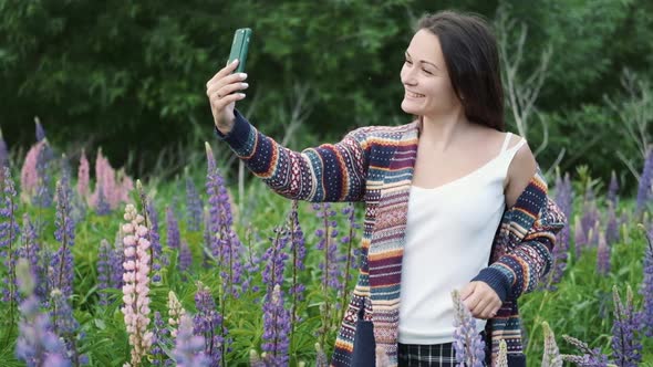 Happy Woman Enjoying the Outdoors Using Her Cell Phone.young Brunette Takes a Selfie on a Background alt