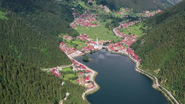 aerial top down view of a mountain village full of homes with red roofs surrounded by mountains and alt