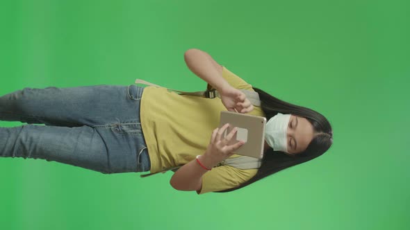 Asian Girl Student Wearing A Mask And Use Tablet While Walking To School On Green Screen Chroma Key alt