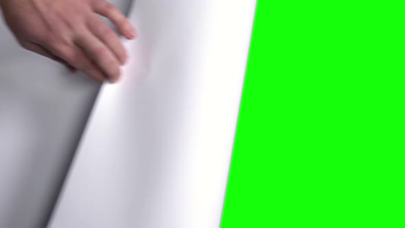 Male Hand Flips a White Sheet of Paper on a Green Screen. alt
