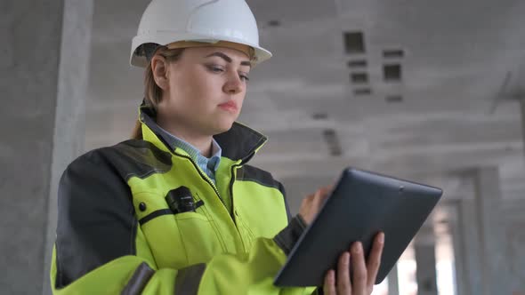 Engineer In Helmets With Tablet Device And Big Paper Drawings Discussing alt