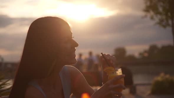 Pretty young woman drinking orange juice at the street cafe