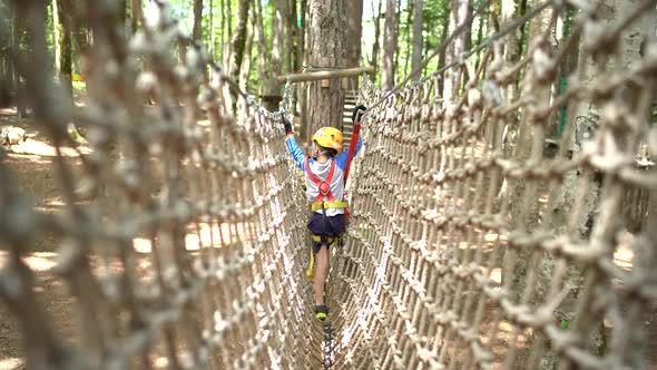 Boy Walking on a Mesh Bridge Holding on to a Cable alt