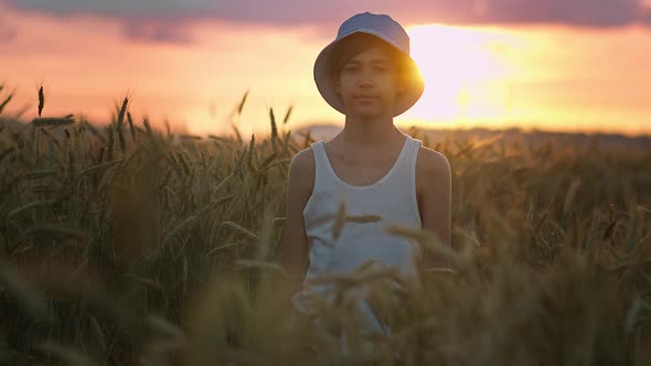 Portrait of a Funny Boy in a Blue Hat in a Wheat Field Looking at the Camera Close Up
