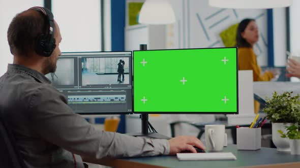 Man Videographer with Headset Working at Greenscreen Computer alt