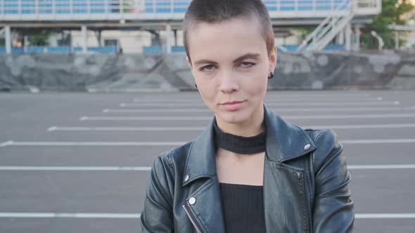 Portrait of Smiling Young Woman with Short Hair in Industrial City Background at Sunset. alt