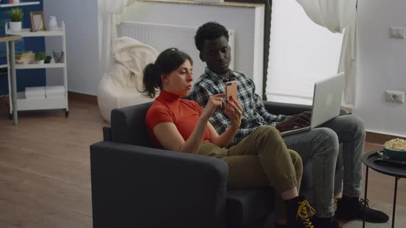 Young Multi Ethnic Couple Using Technology in Living Room alt