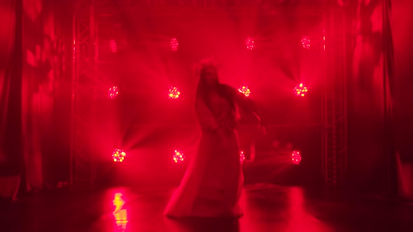 A Woman Dancer Is Silhouetted in Red Lights and Smoke Performing a Folk Dance. A Bright Brunette in alt