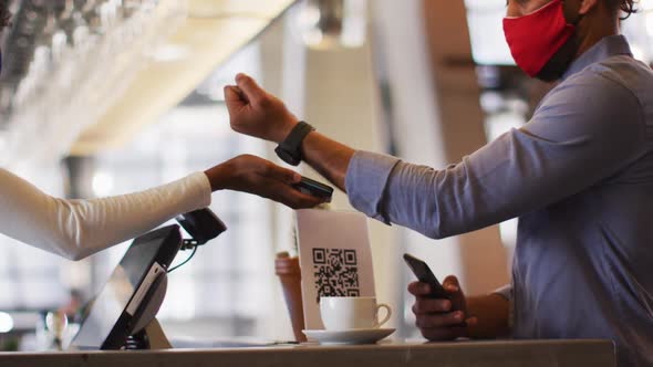 Mixed race man giving african american female cafe worker his smartwatch in order to pay alt