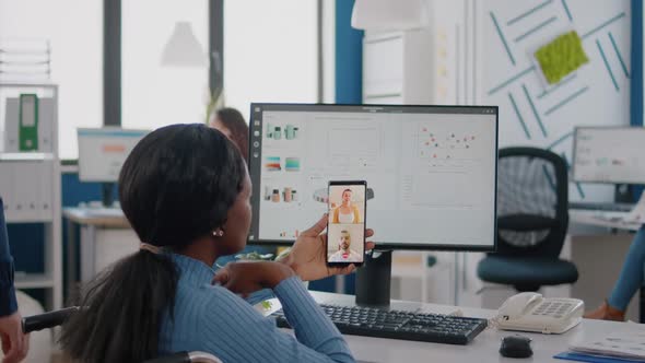Back View of African Woman in Wheelchair Discussing with Friends on Video Call alt