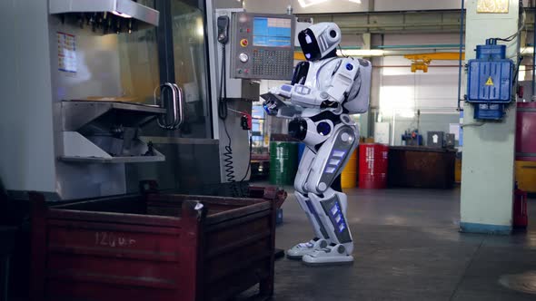 One Droid Checks Machines While Working with a Tablet at a Plant. alt