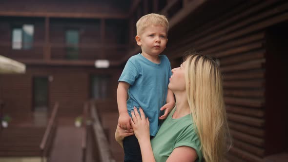 Mother Embraces Little Son on Veranda Deck of Eco Hotel alt
