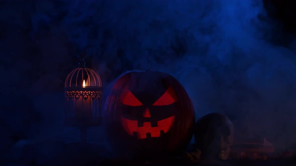Scary laughing pumpkin and an old skull over the frightening gothic background. alt