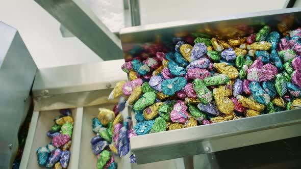Candy Factory. Bunch of Wrapped Candies Falling From Conveyor on Packing Containers in Confectionery alt