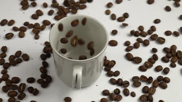 Coffee beans and a white cup, slow motion