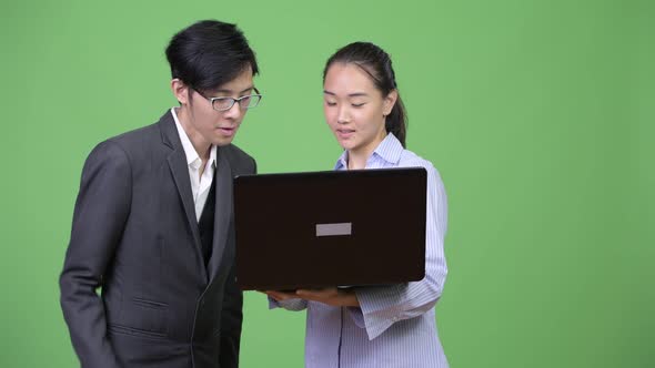 Young Asian Business Couple Using Laptop Together