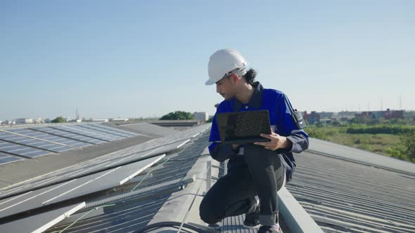 Asian technician inspection solar cell panels field of on roof top factory.