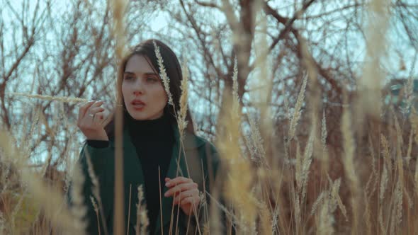 A Young Brunette Among the Reeds Plucks a Straw and Puts It in Her Mouth