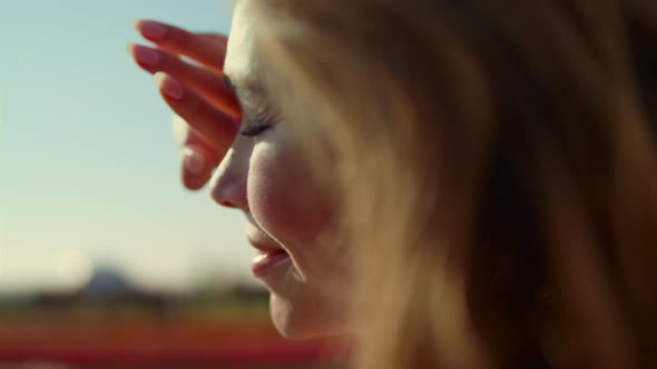 Closeup Pretty Woman Looking at Bright Sunlight in Park with Colorful Flowers alt