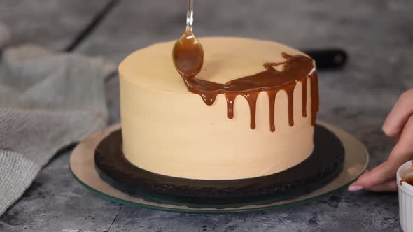 Young Woman Applying Caramel Sauce Onto Delicious Homemade Cake at Table