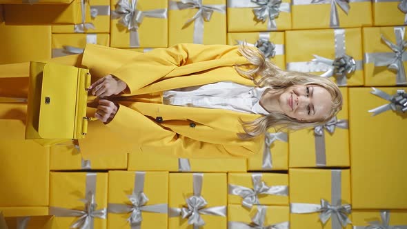 An Emotional Young Woman is Happy to Buy a New Handbag a Woman Dressed in a Yellow Suit Poses on a