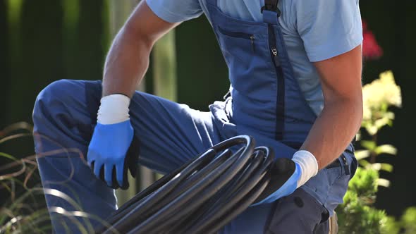Landscaping Worker in His 40s Preparing Irrigation Plastic Pipe For a Drip Irrigation System alt