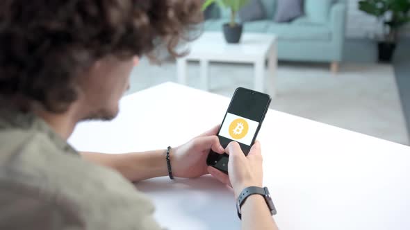 Young Man Looking Concentrated at the Phone in His Hands Thinking About Crypto Bitcoin alt