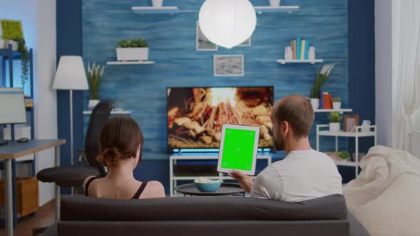 Static Tripod Shot of Couple Holding Vertical Digital Tablet with Green Screen Talking About alt