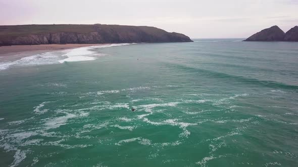 Surfer swims laterally across waves. Drone-shot. Holywell Bay, Newquay, Cornwall. alt