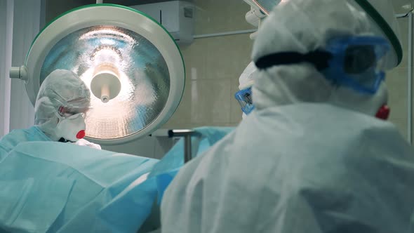 Medical Workers in Safety Suits Are Holding a Surgery alt