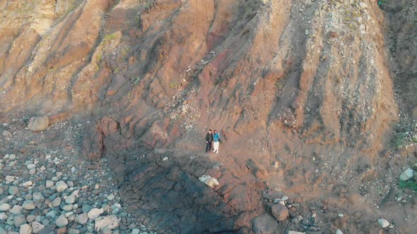 Aerial Shoot. The Camera Moves Away From the Man and Woman Who Stand at the Bottom of the Huge Rocks