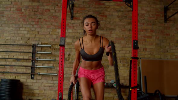 Motivated Fitness Black Female Doing Cross Training with Battle Ropes in Gym alt