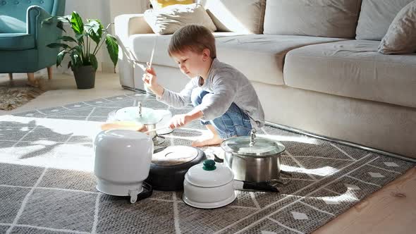 Child Drummer Having Fun Drum Playing on Kitchen Pans at Home alt